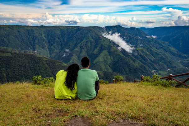 изолированная молодая пара проводит время вместе на вершине холма с горной долиной и драматическое изображение неба принимается на пике Латилум Силлонг Мегхалая Индия. - Фото, изображение