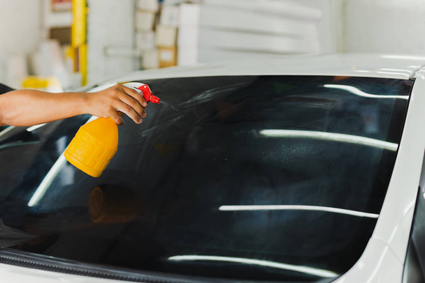 Especialista en coches pulverización de agua en la ventana del coche teñido en el taller. - Foto, Imagen