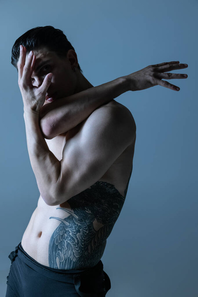 Half-length portrait of young man, flexible male contemp dancer dancing isolated on old navy studio background. Art, motion, inspiration concept. - Photo, Image