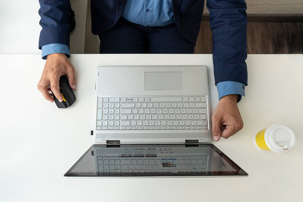 Ο άνθρωπος που εργάζεται με το lap-top, κορυφαία άποψη. επιχειρηματίας στη δουλειά στο γραφείο. έναν υπολογιστή σε ένα λευκό γραφείο και τα χέρια του διευθυντή σε ένα σακάκι. - Φωτογραφία, εικόνα
