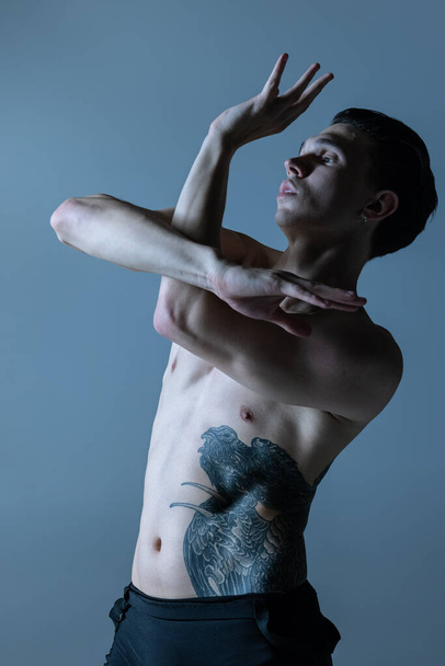 Half-length portrait of young man, flexible male contemp dancer dancing isolated on old navy studio background. Art, motion, inspiration concept. - 写真・画像