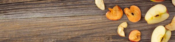 estandarte de Una pila de rebanadas secas de manzanas y manzanas frescas maduras sobre fondo de madera. Patatas fritas secas. Comida vegana saludable - Foto, Imagen