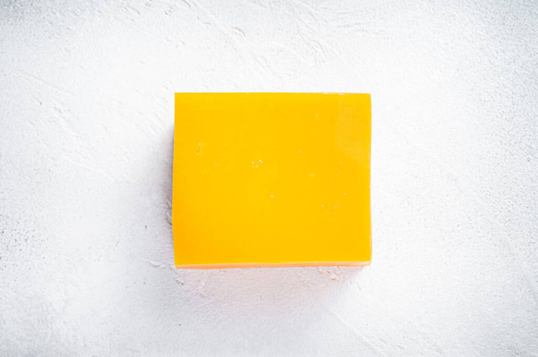Bloco de queijo Cheddar em uma mesa de cozinha. Fundo branco. Vista superior - Foto, Imagem
