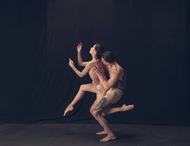 Two flexible dancer, young man and woman in modern art performance isolated on black studio background. Art, motion, inspiration concept. - 写真・画像