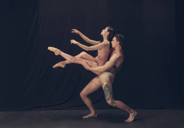Two flexible dancer, young man and woman in modern art performance isolated on black studio background. Art, motion, inspiration concept. - Фото, зображення