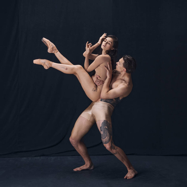 Two flexible dancer, young man and woman in modern art performance isolated on black studio background. Art, motion, inspiration concept. - Valokuva, kuva