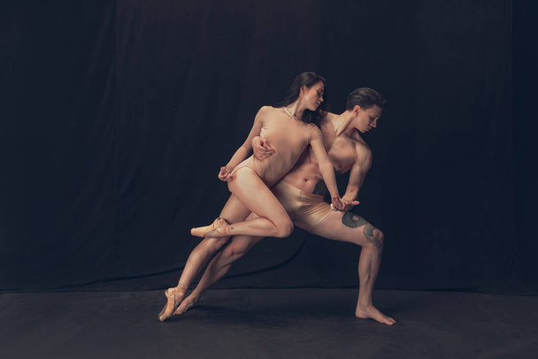 Two flexible dancer, young man and woman in modern art performance isolated on black studio background. Art, motion, inspiration concept. - Foto, Imagen