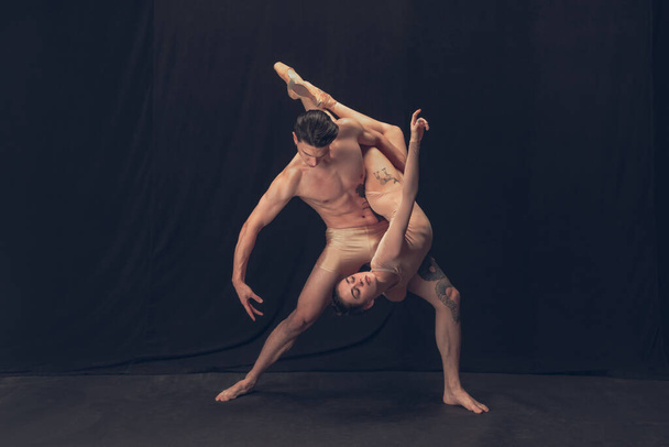 Two flexible dancer, young man and woman in modern art performance isolated on black studio background. Art, motion, inspiration concept. - Фото, изображение