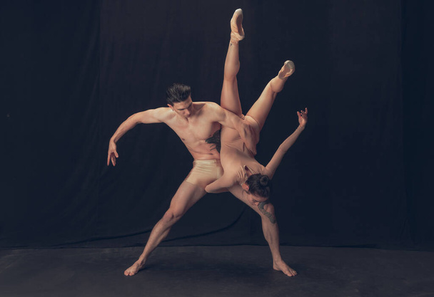 Two flexible dancer, young man and woman in modern art performance isolated on black studio background. Art, motion, inspiration concept. - Fotó, kép