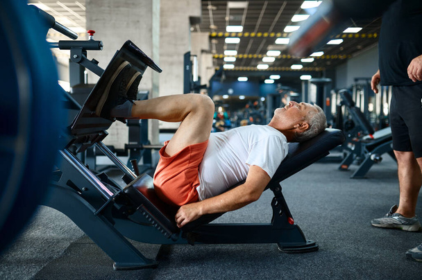 Elderly man on exercise machine in gym - Photo, Image