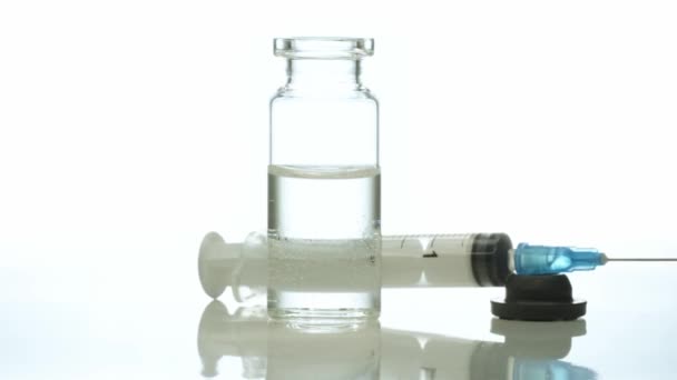 Lääketieteellinen lasipullo lääkeruiskulla pyörii valkoista taustaa vasten - Materiaali, video