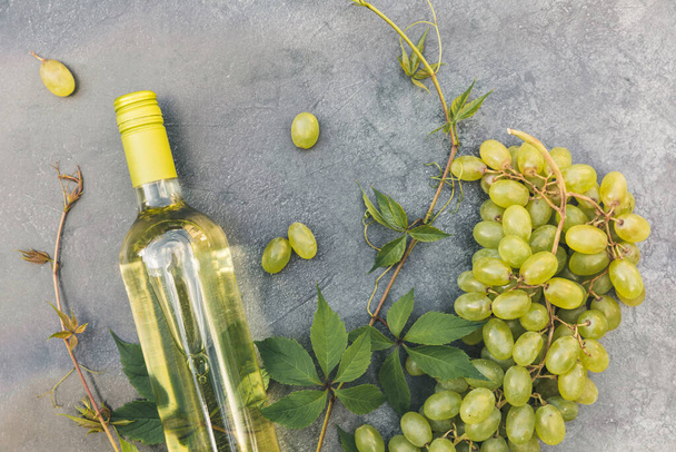 Beyaz şarap, yeşil sarmaşık ve olgun üzümle klasik gri masa arkaplanının en üst görüntüsü. Şarap dükkanı şarap dükkanı ya da şarap tatma konsepti - Fotoğraf, Görsel