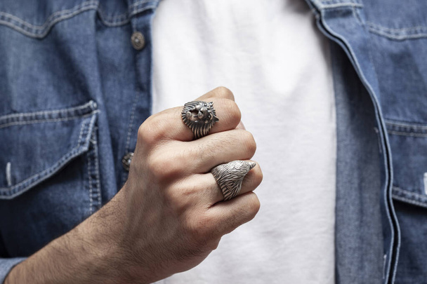 Young male model in a white t-shirt and blue denim shirt holding a silver ring. - Photo, Image