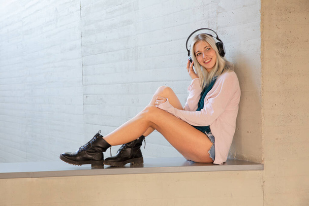 uma jovem loira estudante mulher refrigeração e desfrutar de música com fones de ouvido - Foto, Imagem