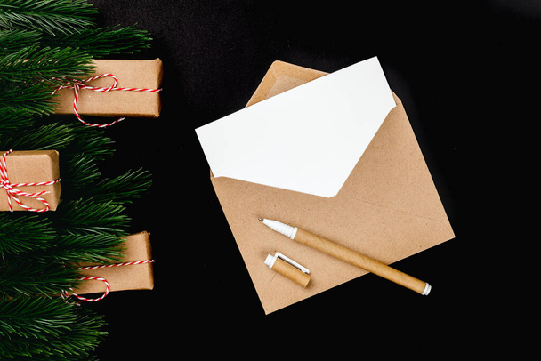 クリスマスグリーティングカードクラフトの文字の材料と黒の孤立した背景にモミの枝とギフトボックス - 写真・画像