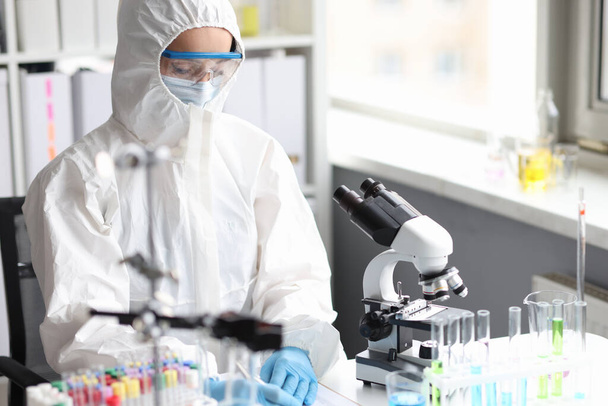 Επιστήμονας σε προστατευτική στολή, μάσκα και γάντια διεξάγει εργαστηριακή έρευνα - Φωτογραφία, εικόνα