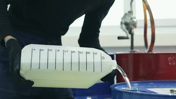 Ein Mann schüttet Benzin oder Motoröl aus einem Kanister in ein Metallfass. Video im 4k-Format - Filmmaterial, Video