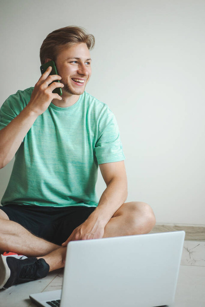 Een man op de vloer die communiceert met iemand die online werkt aan de computer. Zakelijke technologie. Quarantaine levensstijl. - Foto, afbeelding