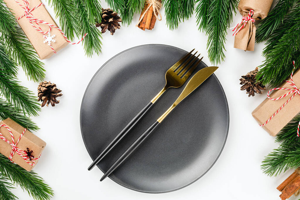 a golden knife and fork on a ceramic black plate on the set table. The concept of a Christmas party in Christmas decorations - Foto, Imagem