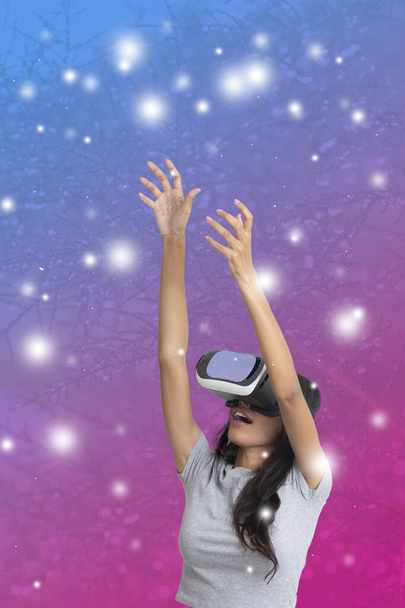 Asian woman playing 3D game with virtual reality eyeglasses extend her hands up  to grab something. - Foto, afbeelding