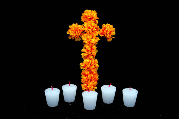 Papel recortado de colores en forma de catrina como decoración para la ofrenda del Día de los Fieles Muertos y Todos los Santos con un cempasuchil en forma de cruz, velas y un marco - Foto, imagen