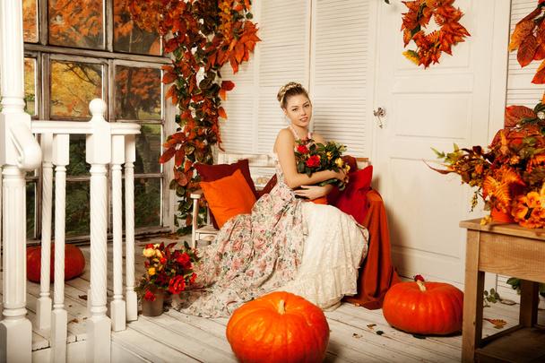 Young woman in vintage dress on autumn porch. Beauty  girl in fa - Photo, image