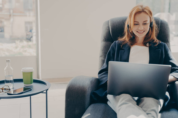 Happy smiling female freelancer during online conference via modern laptop at home - 写真・画像