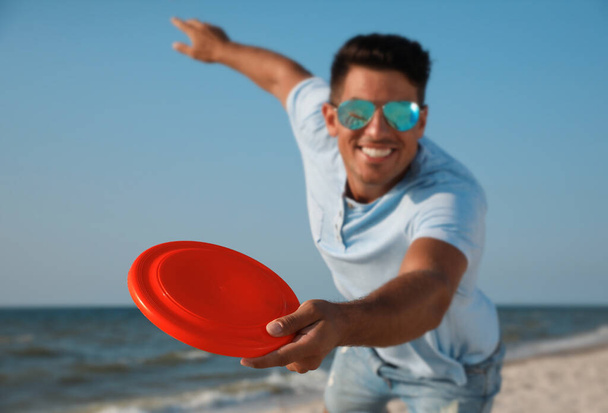 Happy man throwing flying disk at beach, focus on hand - Foto, Bild