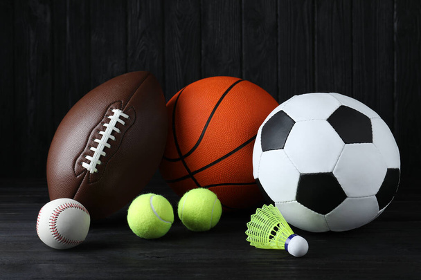 Set of different sport balls and shuttlecock on black wooden table - 写真・画像