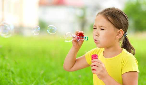 маленька дівчинка дме мильні бульбашки
 - Фото, зображення