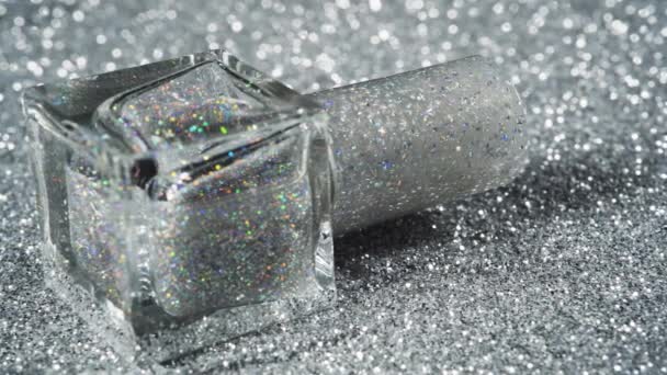 Lassú mozgás mentén az ezüst csillogó körmök lengyel palackban. Fényes háttér - Felvétel, videó