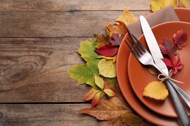 Festive table setting with autumn leaves on wooden background, flat lay. Space for text - Foto, imagen