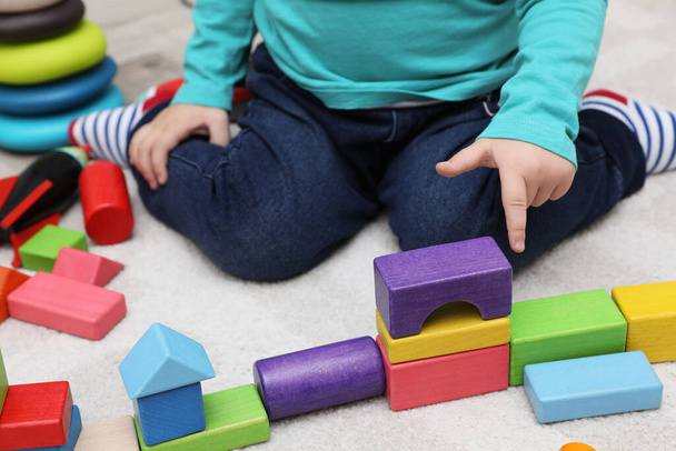 Little child playing with building blocks on carpet, closeup - Photo, image