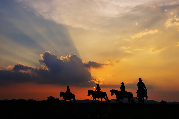 山の景色と夕日の空と馬に乗ってカウボーイシルエット. - 写真・画像