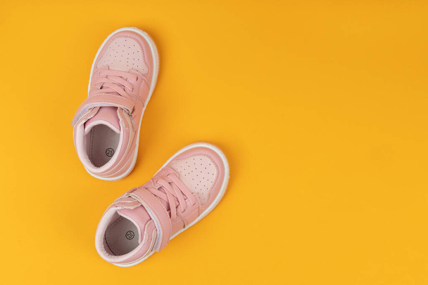 Pink child shoes on yellow background. Children's shoes for girls - Fotoğraf, Görsel