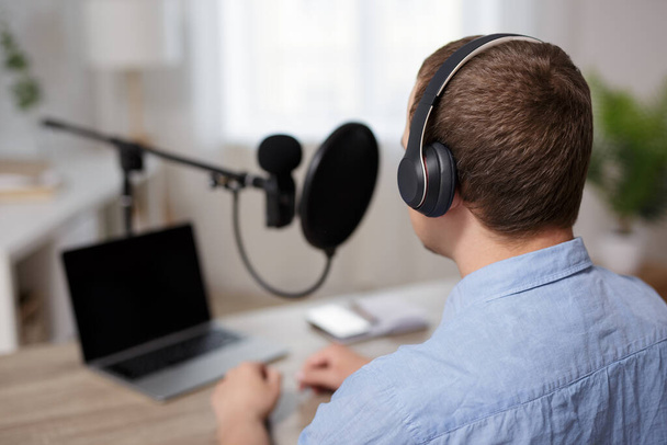 Radio, Podcast und Audio-Blog-Konzept - Rückansicht männlicher Blogger, die Audio-Podcasts oder Talkshows zu Hause aufzeichnen - Foto, Bild