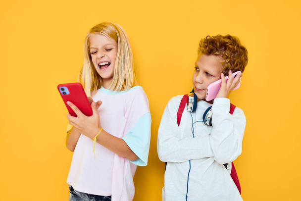 Photo of two small kids girl looking into a smartphone and playing games isolated background - Fotó, kép