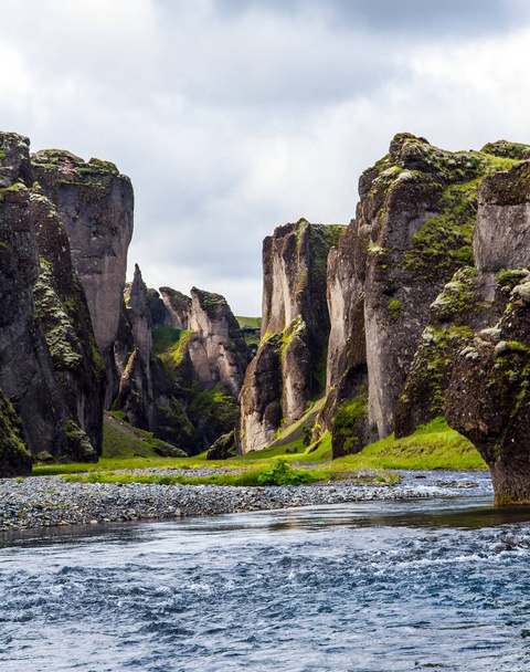 Cloudy summer day. The beautiful and mysterious canyon in Iceland - Fyadrarglyufur. River with glacial water flows between bizarre cliffs. The concept of active, eco and photo tourism - Fotó, kép