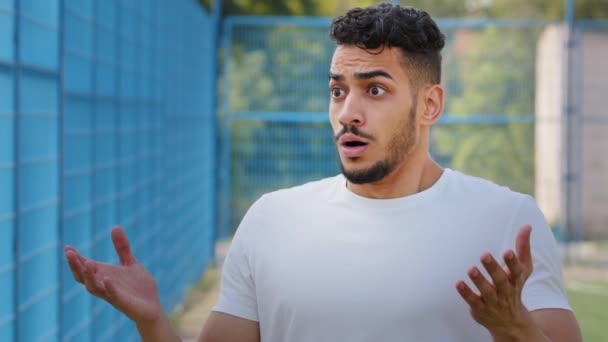 Afraid surprised indignant Middle Eastern Arab athlete in summer sportswear frantically gesturing expressing displeasure, outrage and disagreement. Indian millennial outraged by situation at stadium - Footage, Video
