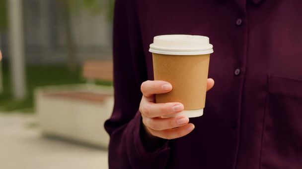 Close-up hand van een zakenvrouw die koffie houdt en met iemand praat. Bekerdetail. - Foto, afbeelding