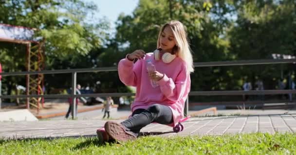 Frau entspannt sich auf Penny-Board und trinkt Wasser - Filmmaterial, Video