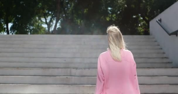 Νεαρή γυναίκα ανεβαίνει τις σκάλες του πάρκου κρατώντας πίνακα δεκάρας - Πλάνα, βίντεο