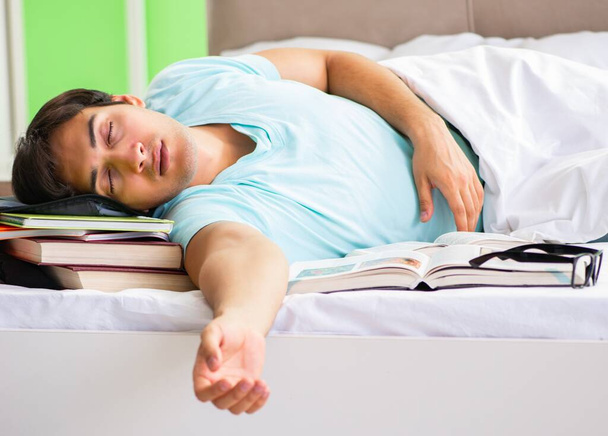 Student przygotowujący się do egzaminów w domu w sypialni leżącej na łóżku - Zdjęcie, obraz