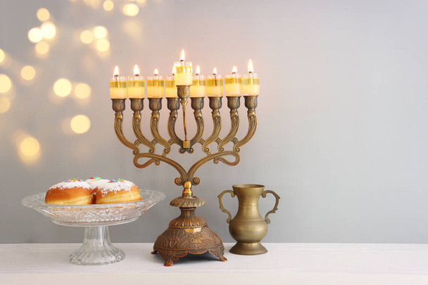 Religion image of jewish holiday Hanukkah background with menorah (traditional candelabra), doughnut and oil candles - Photo, Image