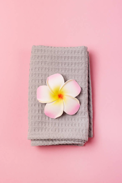 Beautiful Spa Composition on Pink Background Gray Towel and Plumeria Flower Vertical - Foto, Bild