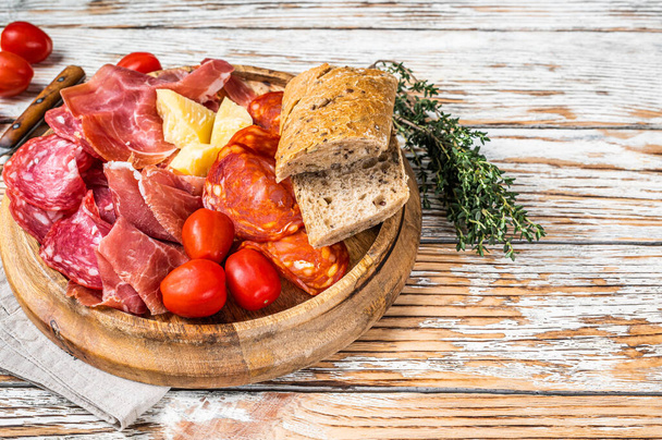 Cold meat plate, charcuterie traditional Spanish tapas on a wooden board. White wooden background. Top view. Copy space - Foto, Imagen