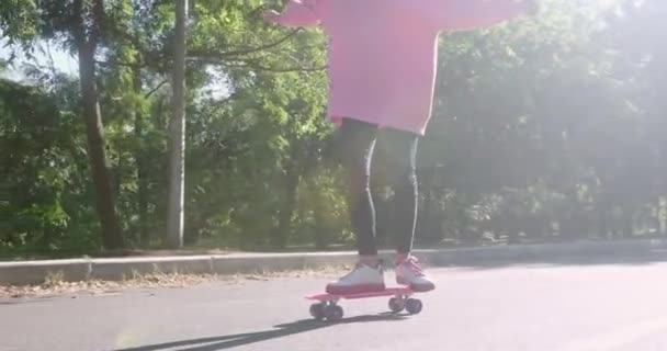 Młoda kobieta łyżwy trzęsie się na tablicy penny na drodze park - Materiał filmowy, wideo