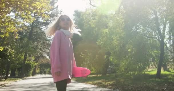 Γυναίκα με ακουστικά περπατά στο δρομάκι πάρκο και στροφές που θέτουν - Πλάνα, βίντεο