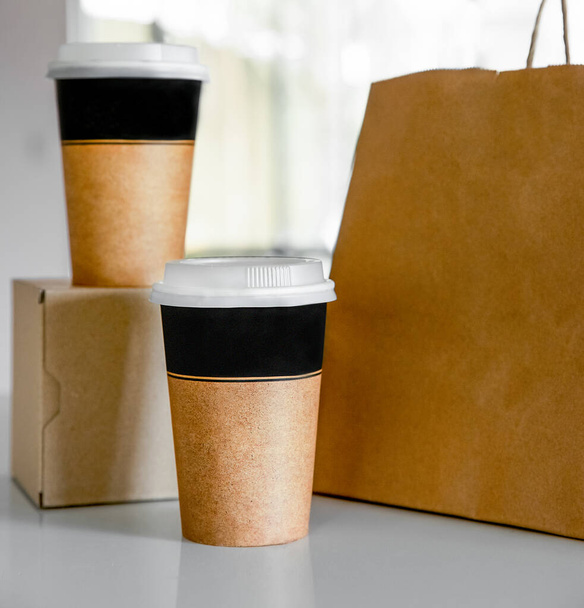koffie in kartonnen bruine bekers besteld en geleverd voor afhaalmaaltijden, levering van voedsel, afhaalmaaltijden, kopieerruimte voor tekst - Foto, afbeelding