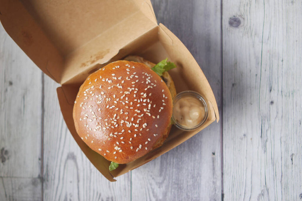 burger de bœuf et frites dans une boîte en papier à emporter sur la table  - Photo, image